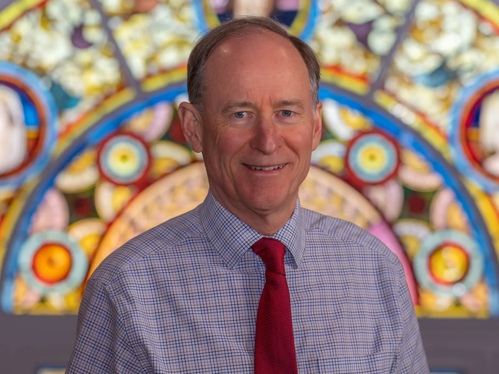 Smiling older gentleman in front of stain glass window