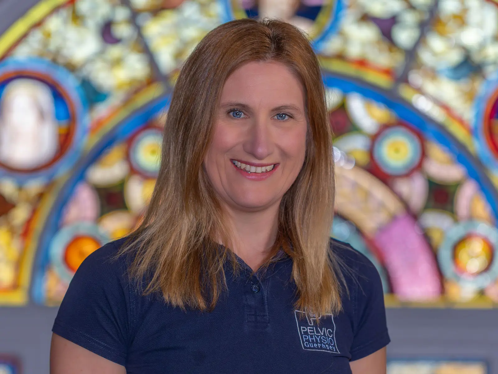 Smiling red haired lady in front of stain glass window